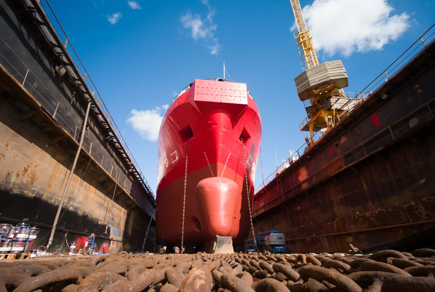 Der Bug eines Schiffes im Trockendock unter einem Werftkran.