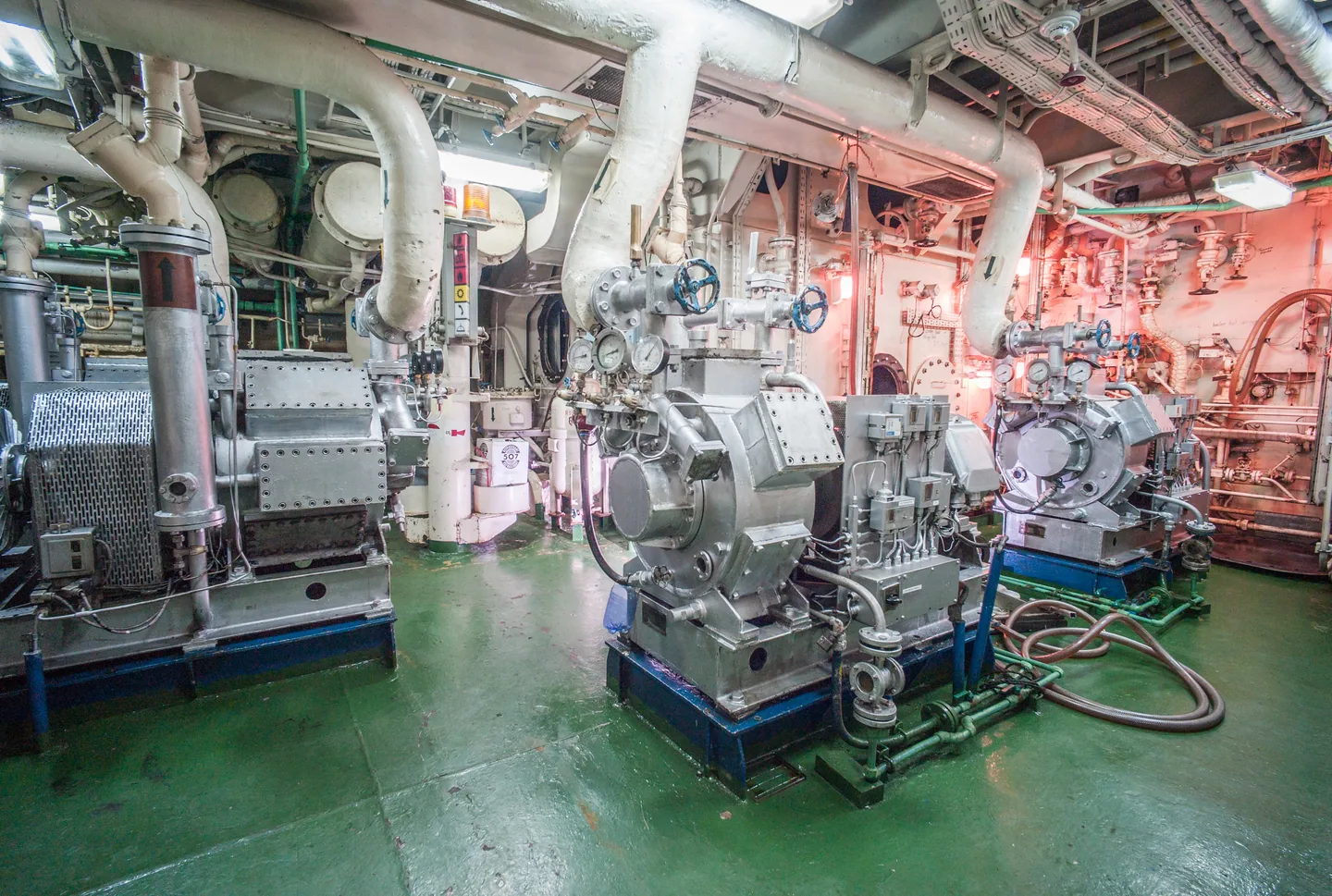 Maschinen, Rohrleitungen und Druckanzeigen im Maschinenraum eines Schiffes.